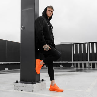 guy shows off orange trainers for men