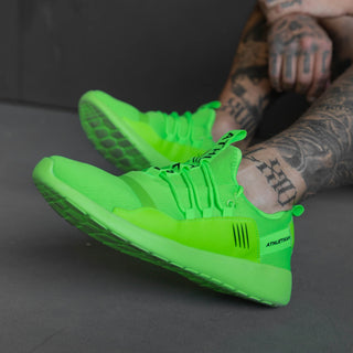 tattooed make model shows angled shot of fluro green sneakers